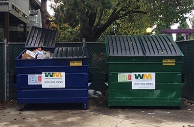 dumpster enclosure at multifamily property showing recycle and garbage dumpsters side by side