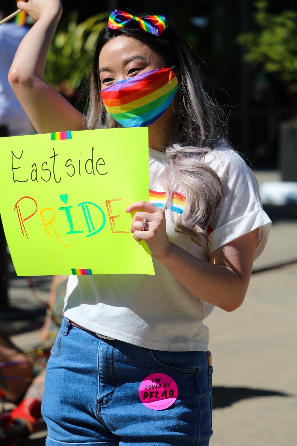 Person in rainbow mask with sign that says eastside pride