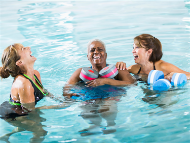 Photo of three women laughing at an aquatic exercise class