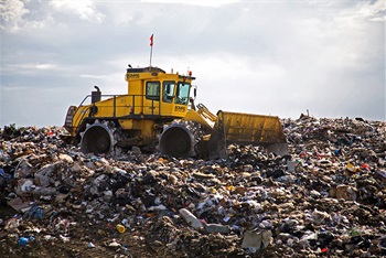 yellow tractor atop a pile of mixed trash at the Cedar Hills Landfill