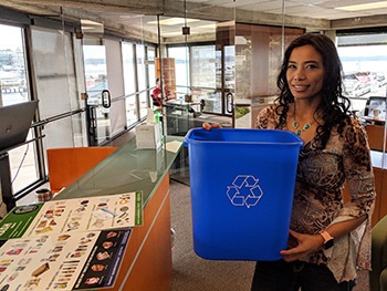 woman holds free recycling bin next to counter at kirkland business