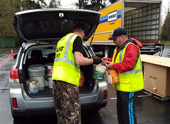 event staff removing latex paint from back of car at paint recycling event