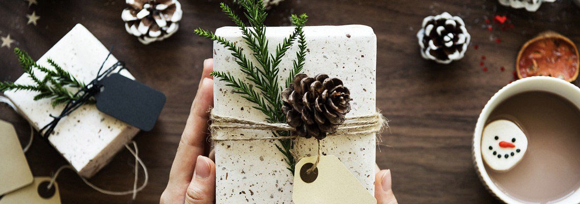 person holding wrapped gift with natural compostable decorations