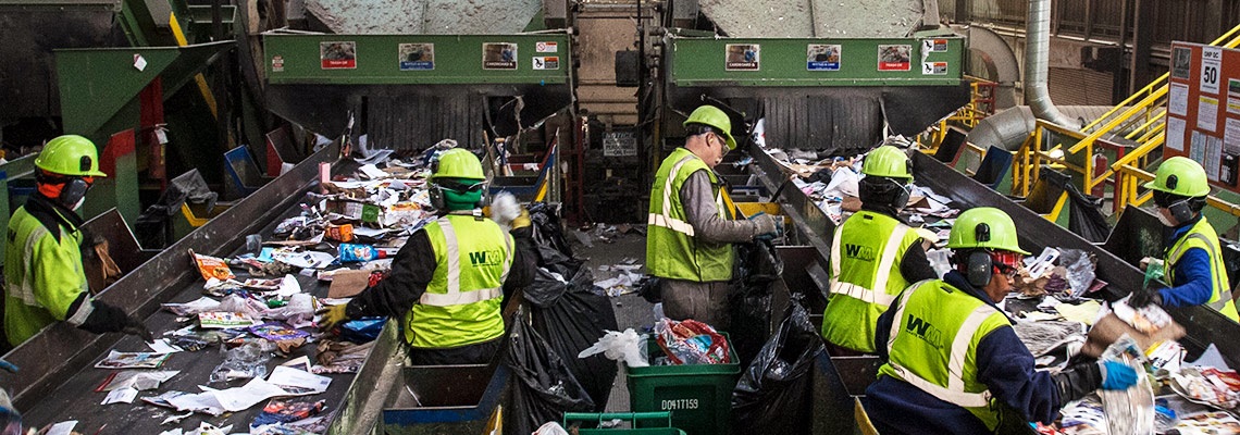 workers at the Cascade Recycling Center sort plastic contamination out of paper on conveyor belts