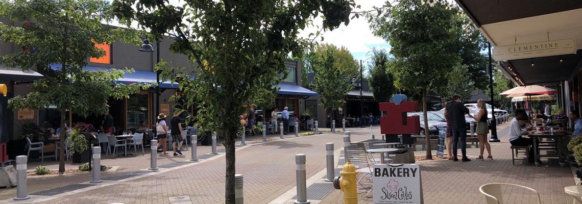 people eating, talking and walking on Park Lane in downtown Kirkland, with sandwich boards and public art and sidewalk seating