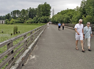 older couple walking on boardwalk at Juanita Bay Park with water covered in lily pads