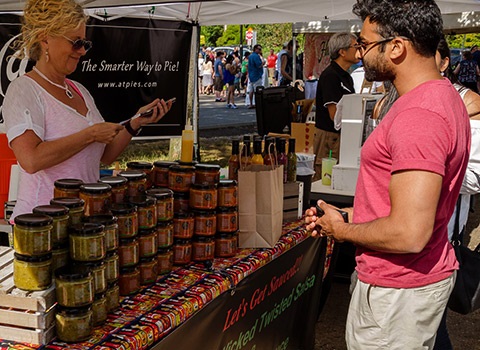 Indian man buying salsa at Juanita farmers market