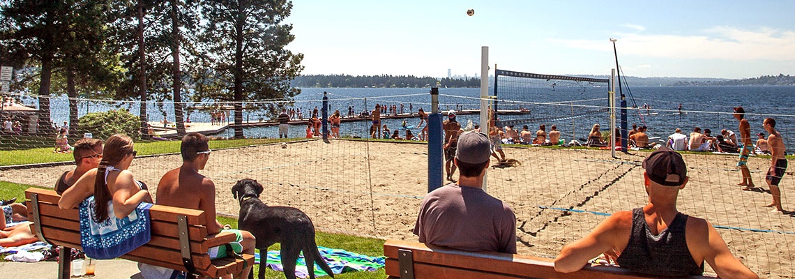 people watching a volleyball game from benches at a waterfront park