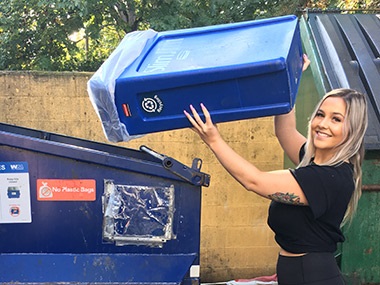employee at business dumping recycling loose into dumpster