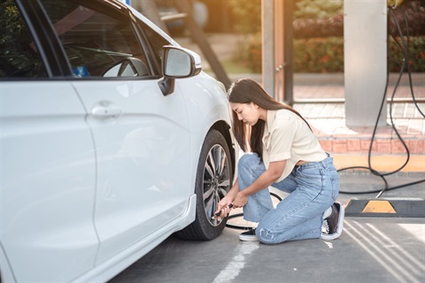 Person inflating car tires with air pump