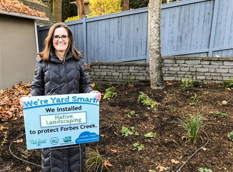 Resident Holding Yard Smart Sign in front of native plantings