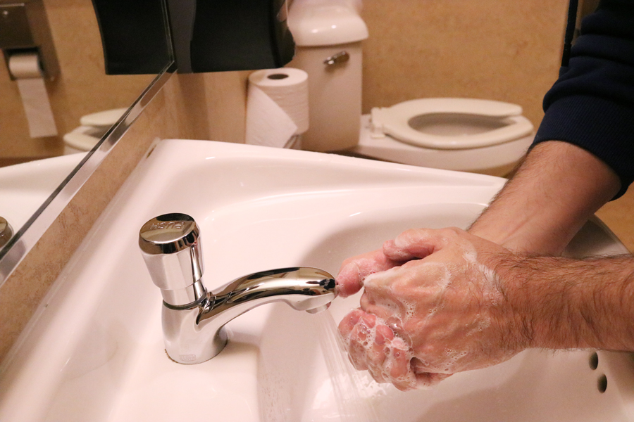 Hands being washed in a bathroom sink.