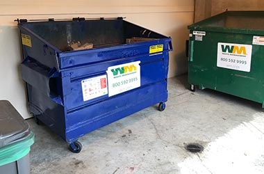garbage and recycling dumpsters at commercial mixed use property with food waste cart