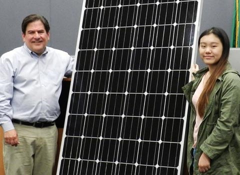Jay Arnold and resident advocate (young Asian woman with long hair) holding a solar panel that was later installed at City Hall