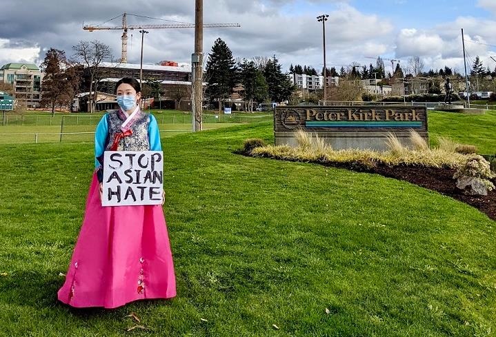Image of beautiful Korean woman wearing pink dress and holding a sign that says Stop Asian Hate